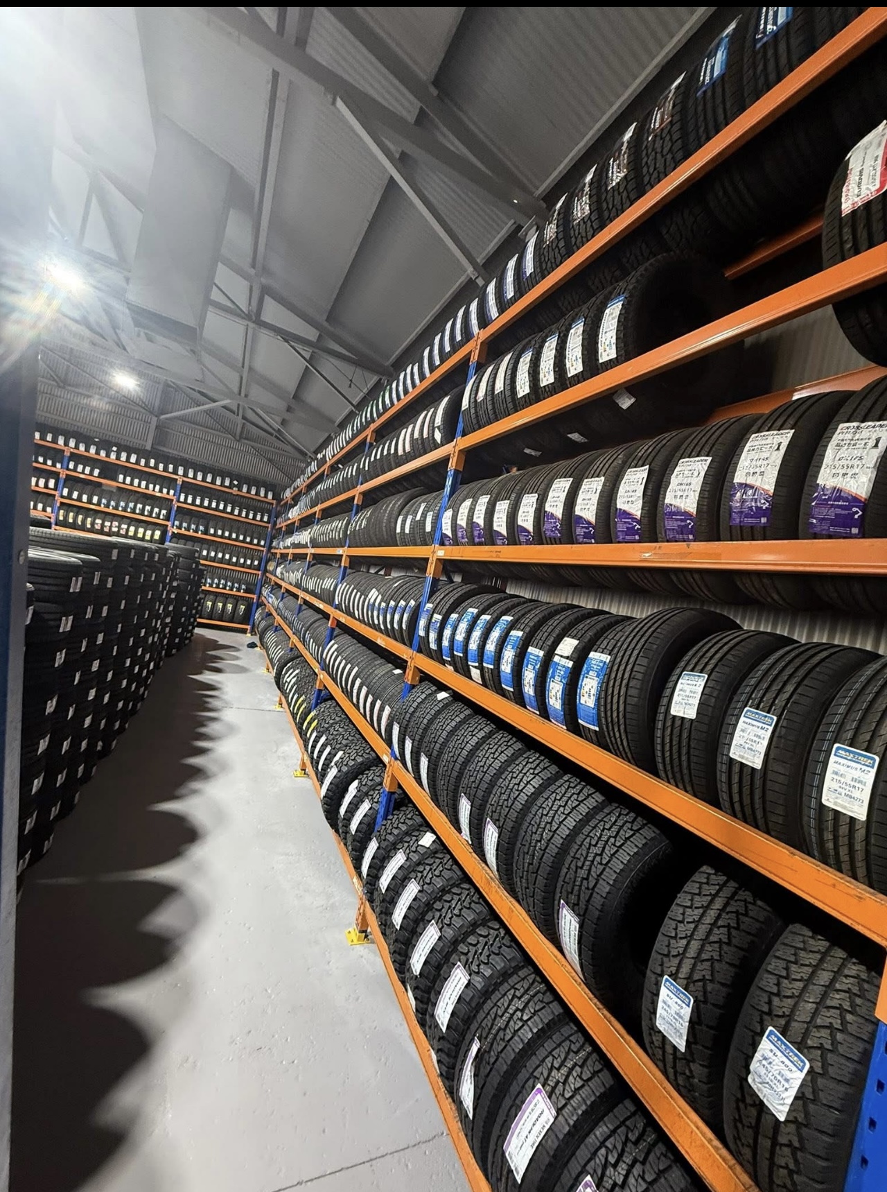 An aisle of racking at All Budget Tyres stocked from floor to ceiling with tyres in many sizes