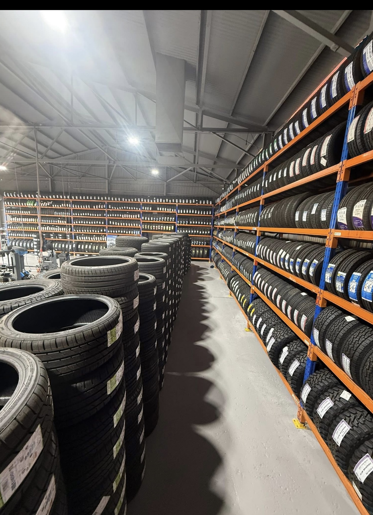 Racking at All Budget Tyres stacked floor to ceiling with tyres, and more stacked on the floor